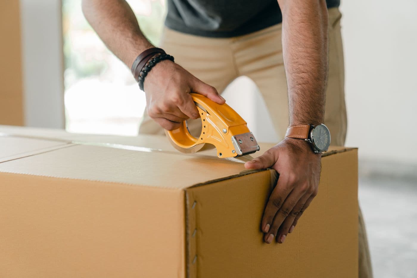 Hands carefully taping a cardboard carton