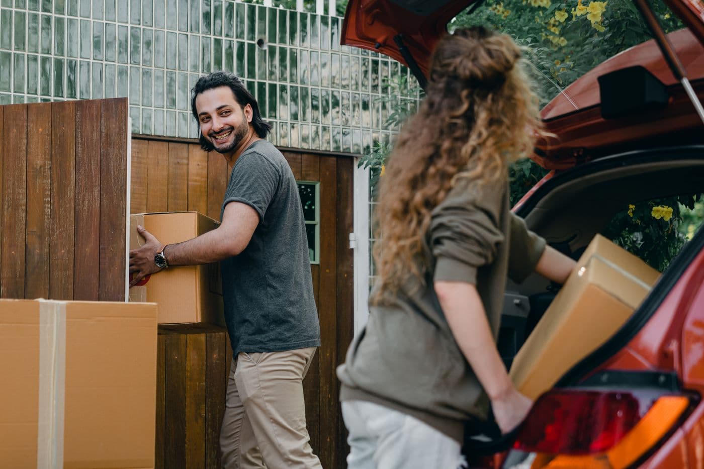 People carrying moving boxes to a vehicle